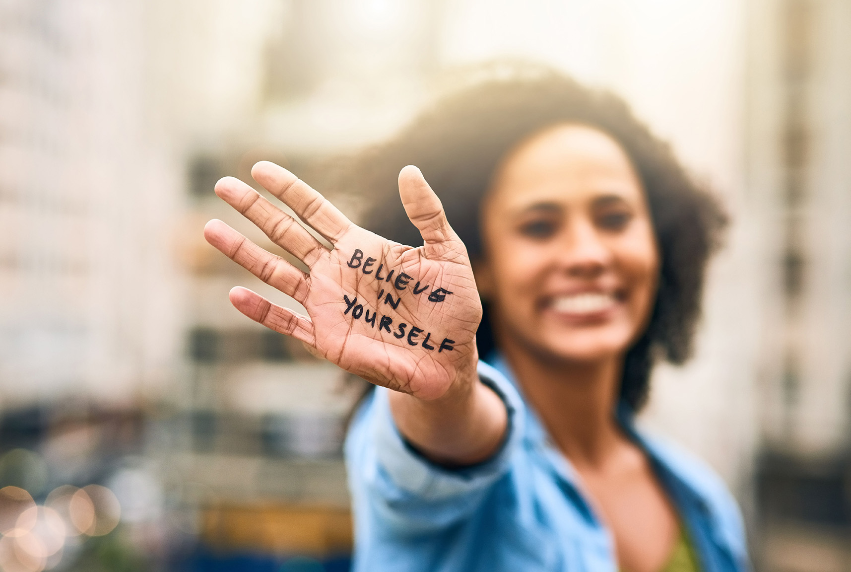 A woman holding her hand up to show the word " believe in yourself ".