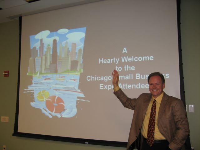 A man in a suit and tie standing next to a projection screen.