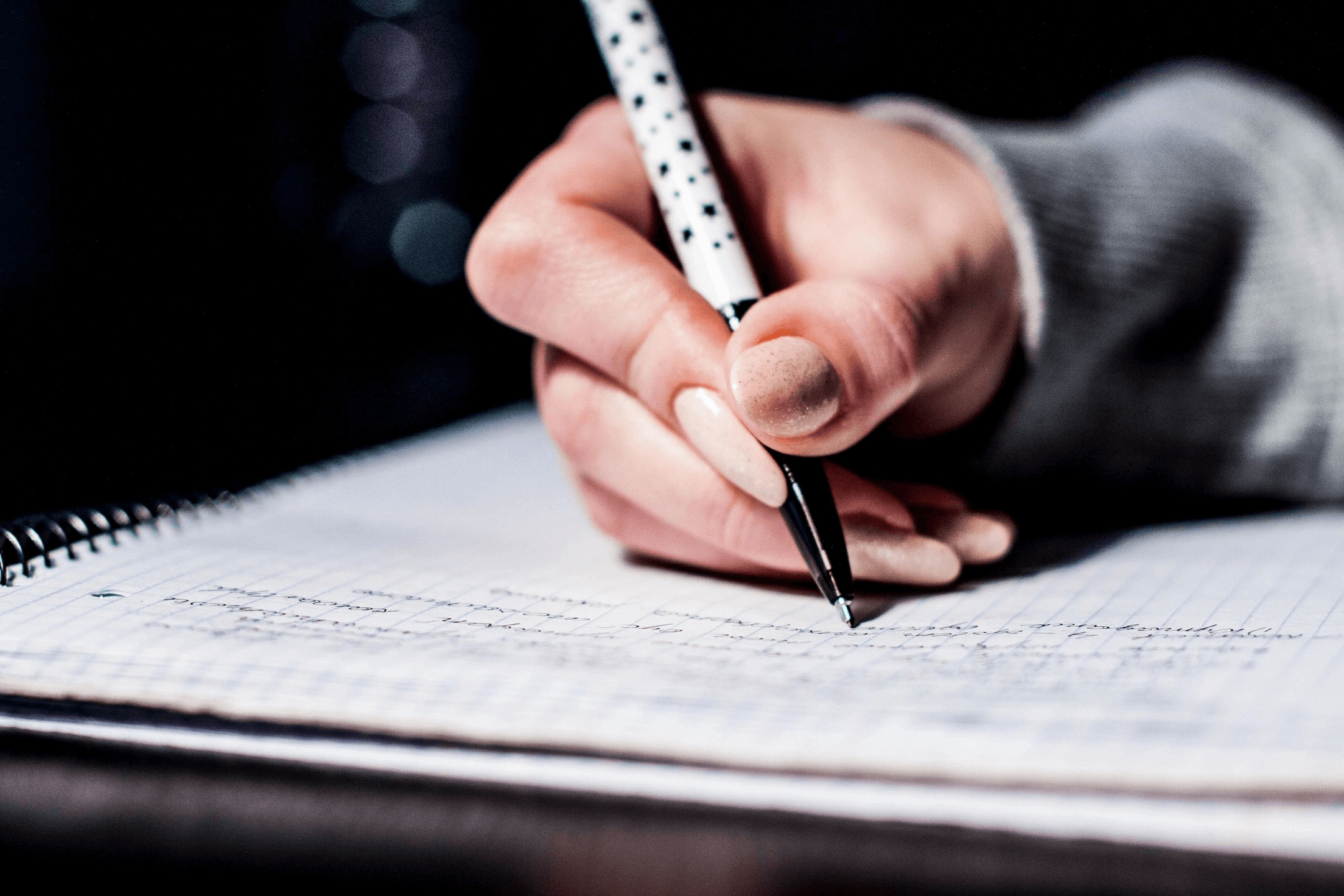 Person writing notes with a pen on lined paper.