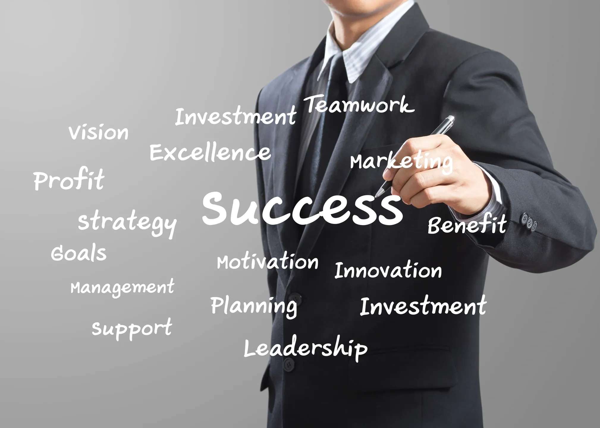 Businessman in suit writing "Success" among buzzwords
